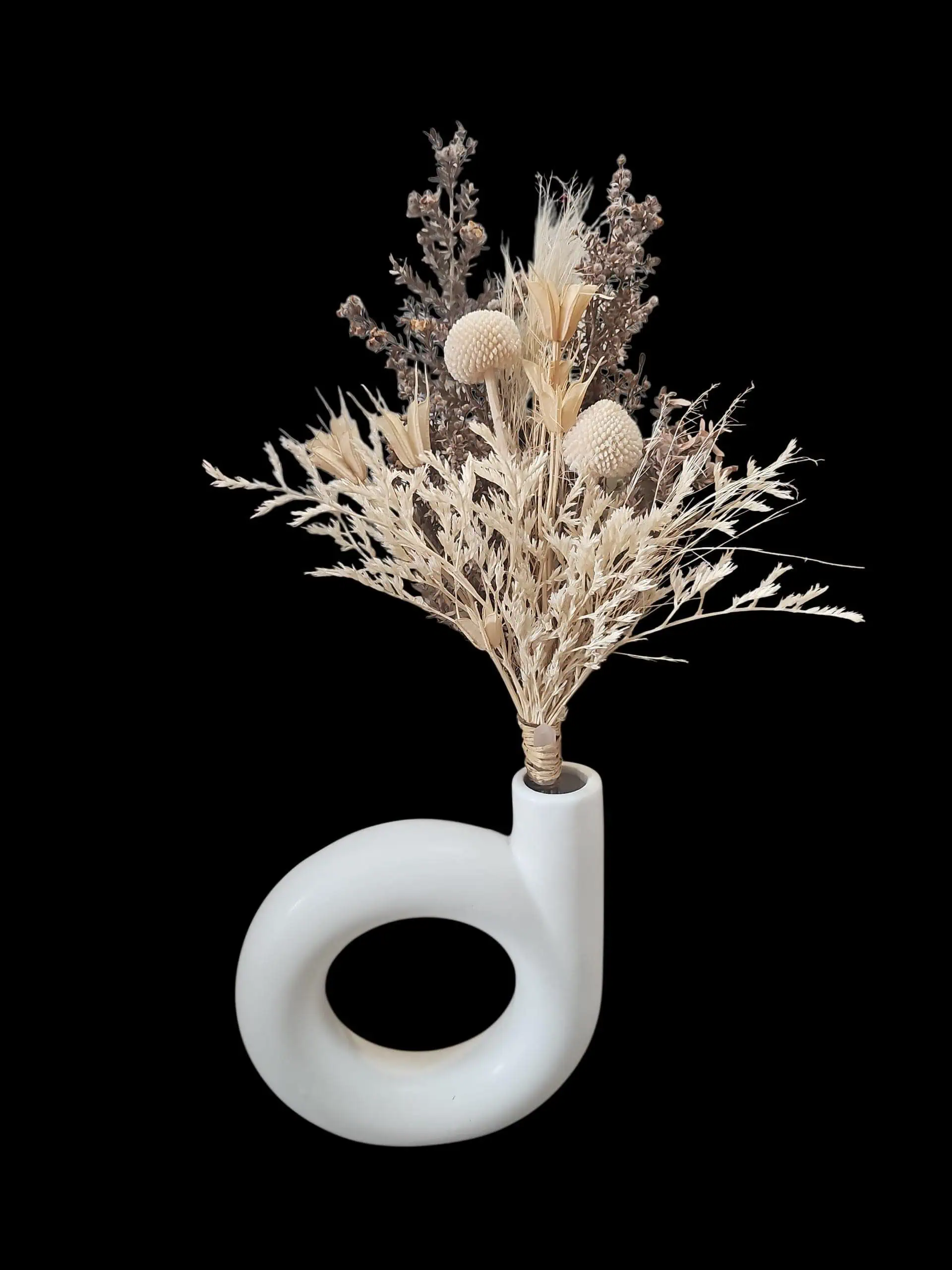 White ceramic loop vase with a neutral preserved dried flower arrangement