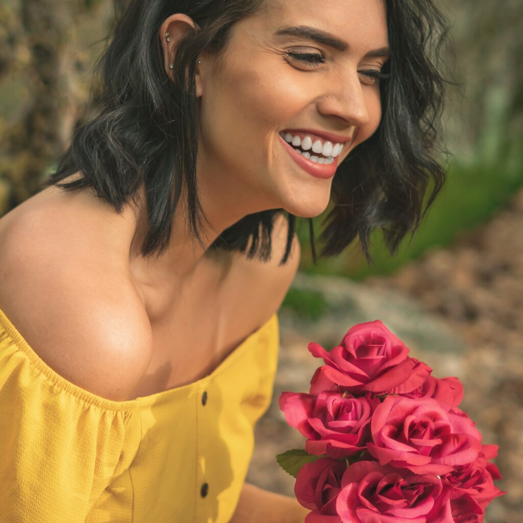 The woman was smiling happily as she held a bouquet of red roses.